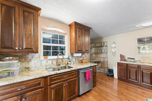 kitchen featuring dishwasher, light wood-type flooring, sink, and tasteful backsplash