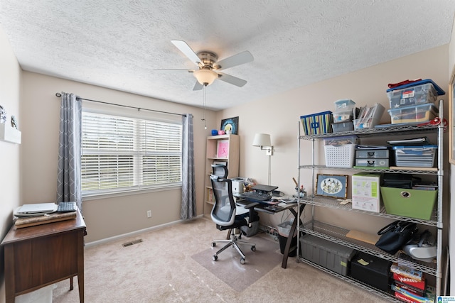 carpeted office space with a textured ceiling and ceiling fan