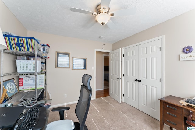 home office with a textured ceiling, ceiling fan, and light carpet