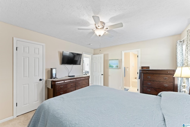 bedroom with a textured ceiling, ceiling fan, light carpet, and connected bathroom