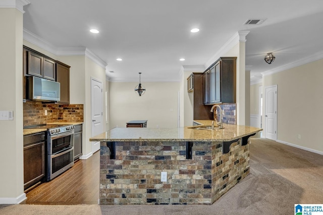 kitchen with light stone countertops, tasteful backsplash, stainless steel appliances, sink, and hardwood / wood-style flooring