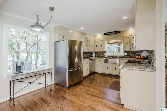 kitchen with decorative backsplash, appliances with stainless steel finishes, crown molding, sink, and hardwood / wood-style flooring