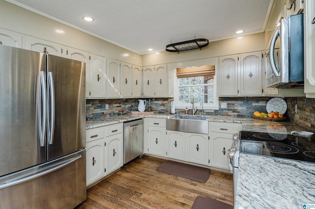 kitchen featuring white cabinetry, sink, light stone countertops, dark hardwood / wood-style flooring, and appliances with stainless steel finishes