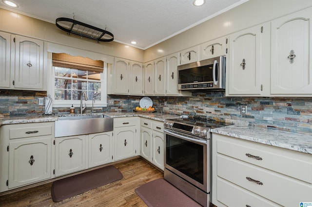 kitchen featuring white cabinetry, wood-type flooring, sink, and appliances with stainless steel finishes