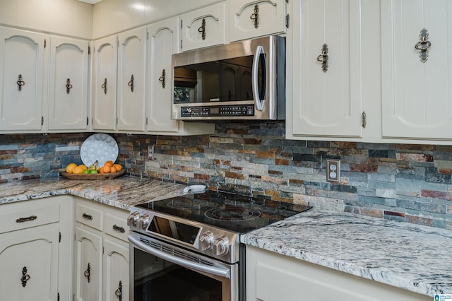 kitchen featuring backsplash, stainless steel appliances, white cabinetry, and light stone counters