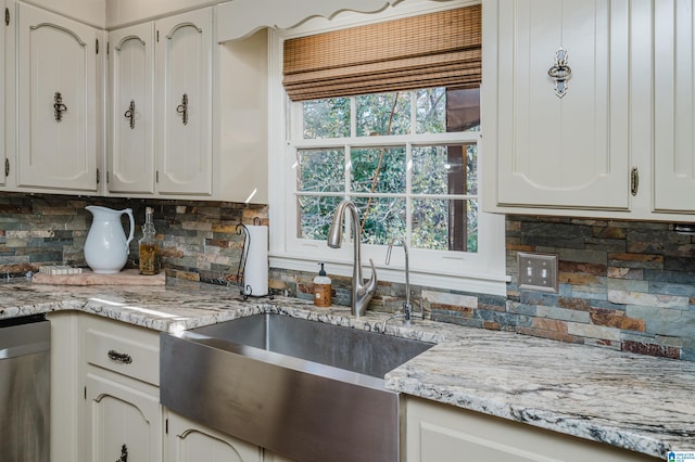 kitchen featuring tasteful backsplash, sink, white cabinets, and stainless steel dishwasher