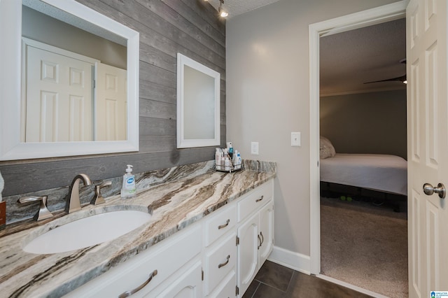 bathroom with vanity, wooden walls, tile patterned flooring, ceiling fan, and a textured ceiling