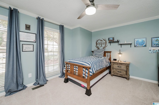 carpeted bedroom with a textured ceiling, ceiling fan, and crown molding