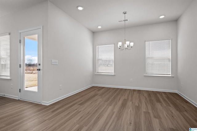 unfurnished dining area with an inviting chandelier and dark hardwood / wood-style flooring