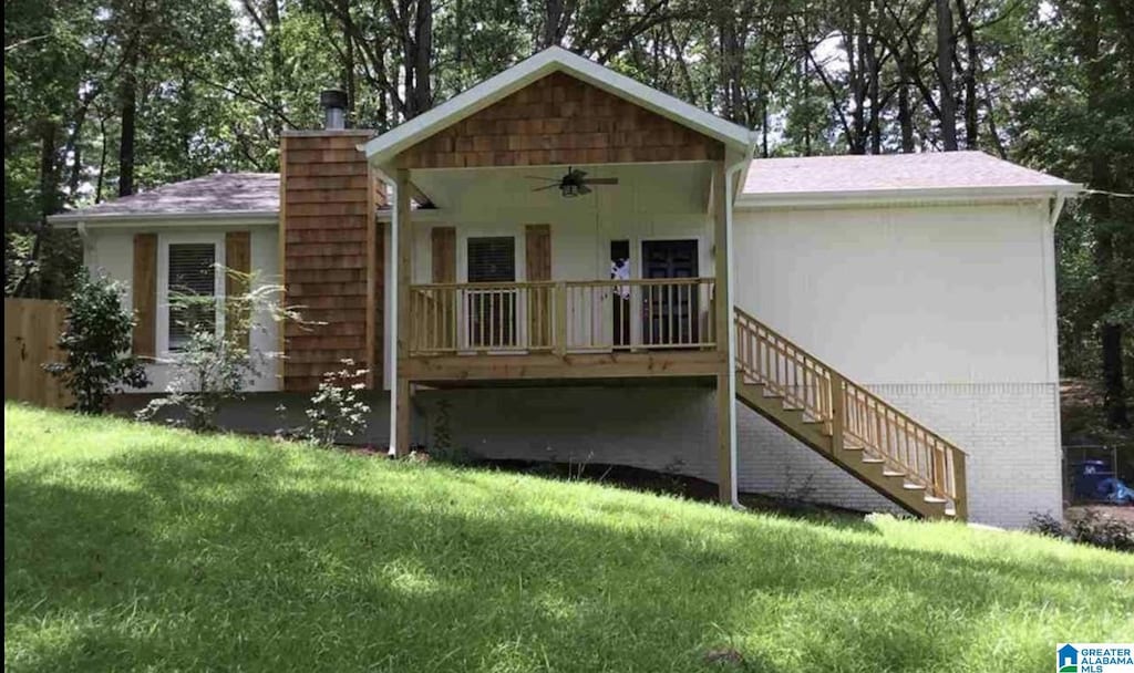 rear view of house with ceiling fan and a yard