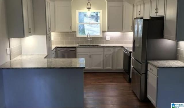 kitchen with light stone countertops, appliances with stainless steel finishes, dark hardwood / wood-style flooring, sink, and white cabinetry