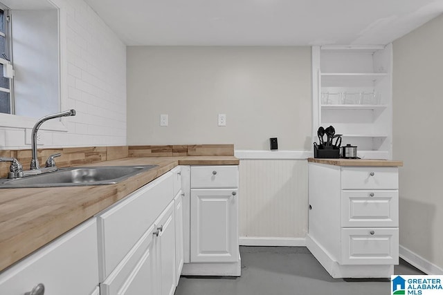 kitchen featuring wood counters, white cabinetry, and sink