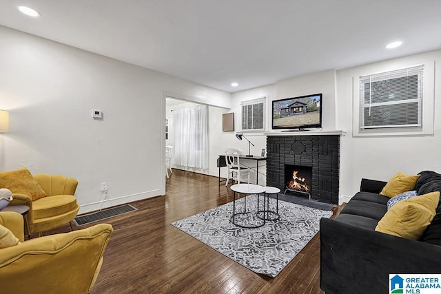 living room featuring dark hardwood / wood-style floors and a brick fireplace