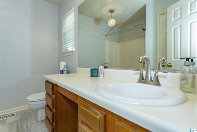 bathroom with walk in shower, vanity, a textured ceiling, hardwood / wood-style flooring, and toilet