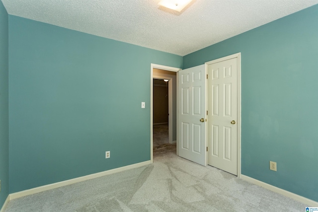 unfurnished bedroom with a closet, light colored carpet, and a textured ceiling