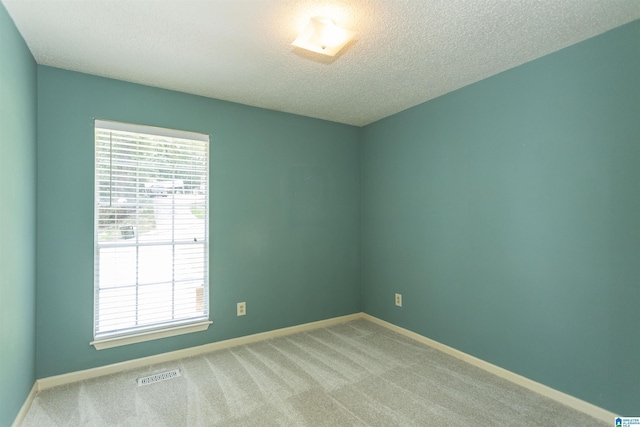 spare room featuring carpet flooring and a textured ceiling