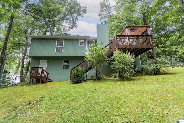 rear view of property featuring a wooden deck and a lawn