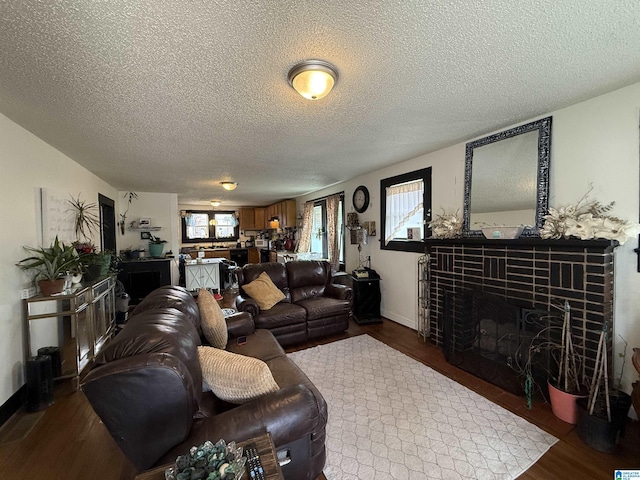 living room with a textured ceiling, baseboards, dark wood-style flooring, and a tile fireplace