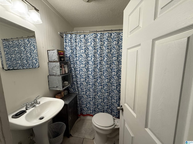 bathroom with a shower with curtain, a sink, a textured ceiling, tile patterned floors, and toilet