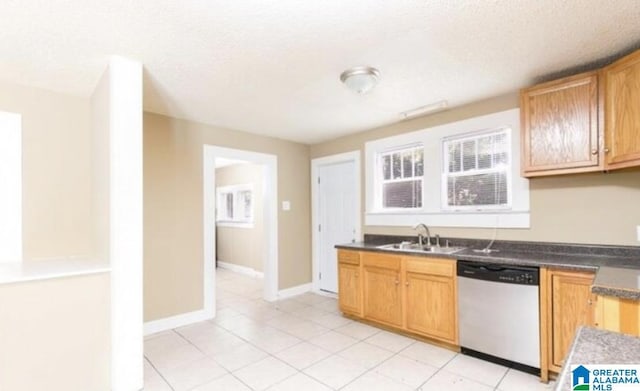 kitchen with dishwasher, dark countertops, baseboards, and a sink