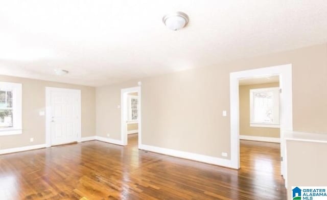 empty room with a healthy amount of sunlight, baseboards, and wood finished floors