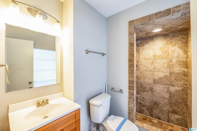 bathroom with vanity, toilet, and tiled shower