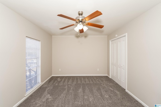 empty room with dark colored carpet and ceiling fan