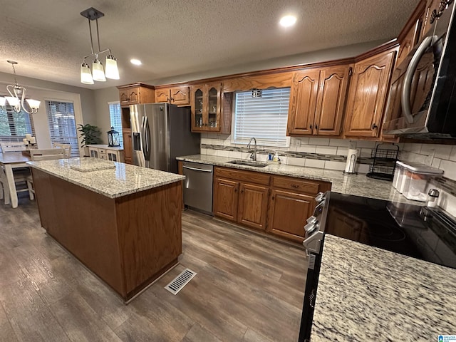 kitchen with stainless steel appliances, sink, pendant lighting, a chandelier, and dark hardwood / wood-style floors