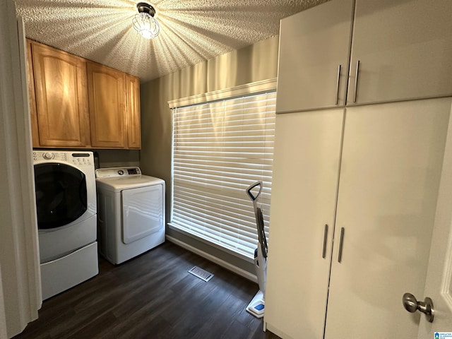 laundry room with cabinets, a textured ceiling, separate washer and dryer, and dark wood-type flooring