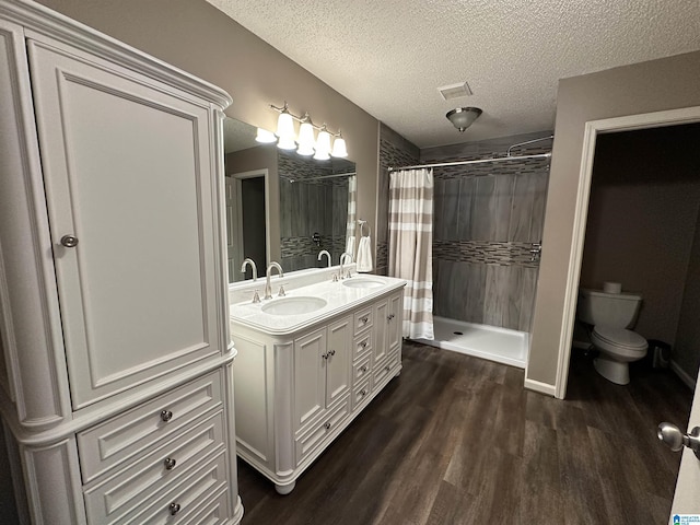 bathroom featuring a shower with shower curtain, a textured ceiling, vanity, hardwood / wood-style floors, and toilet