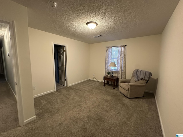 sitting room with a textured ceiling and dark carpet