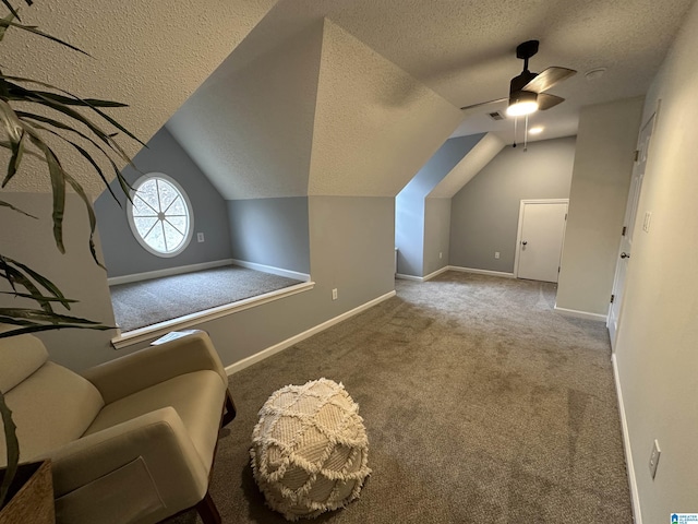 unfurnished room featuring a textured ceiling, carpet floors, vaulted ceiling, and ceiling fan