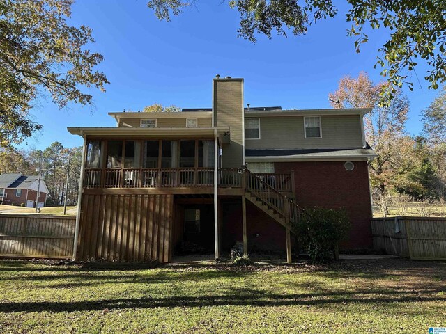 back of house featuring a yard, a wooden deck, and a sunroom