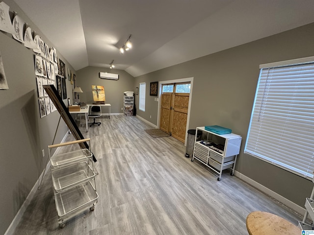 office area with wood-type flooring, a wall unit AC, and vaulted ceiling