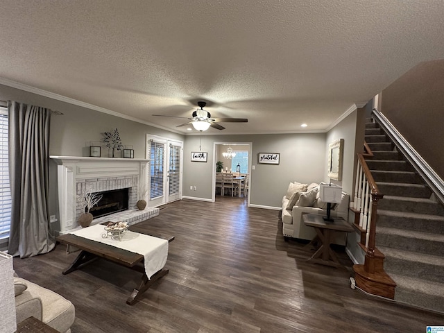 living room with dark wood-type flooring, a brick fireplace, ceiling fan, ornamental molding, and a textured ceiling