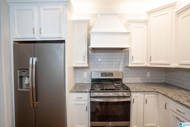 kitchen featuring light stone countertops, appliances with stainless steel finishes, decorative backsplash, custom range hood, and white cabinetry