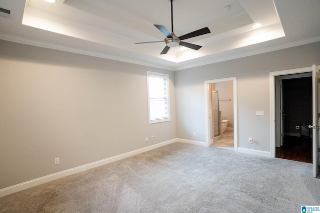 unfurnished bedroom with ensuite bathroom, ceiling fan, a raised ceiling, and crown molding