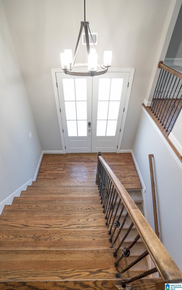 stairway with hardwood / wood-style floors and a chandelier