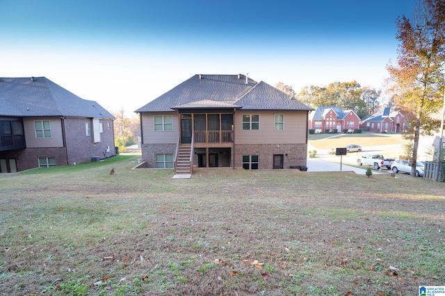 back of property with a sunroom, a yard, and central AC unit