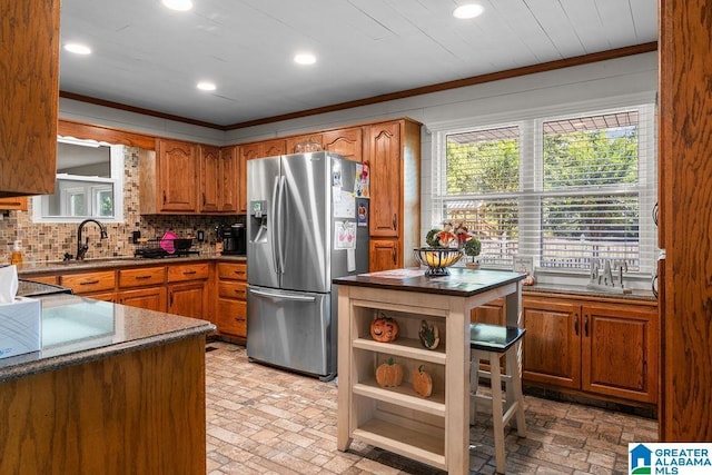 kitchen with decorative backsplash, stainless steel fridge, ornamental molding, and sink