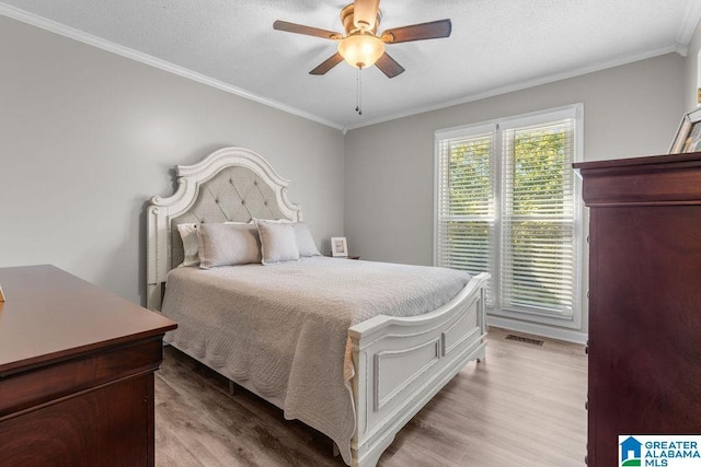 bedroom with a textured ceiling, light hardwood / wood-style floors, ceiling fan, and ornamental molding