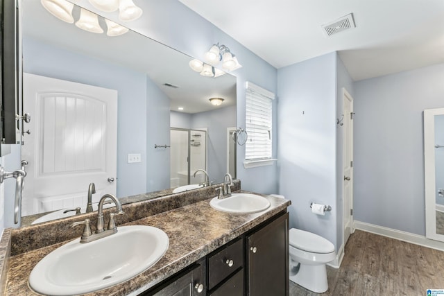 bathroom featuring vanity, hardwood / wood-style flooring, toilet, and a shower with door