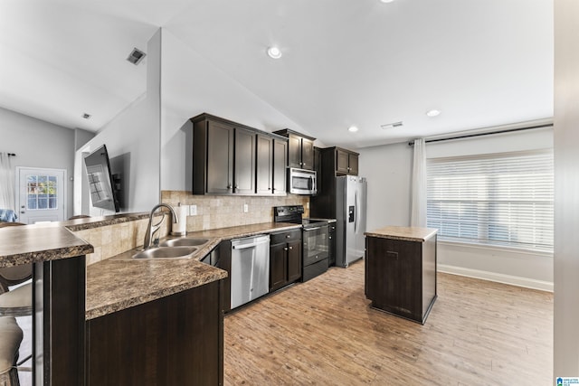 kitchen with a center island, lofted ceiling, sink, and appliances with stainless steel finishes