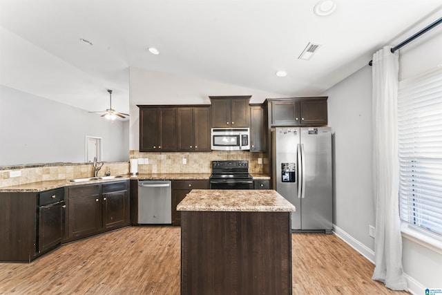 kitchen with lofted ceiling, sink, appliances with stainless steel finishes, and light hardwood / wood-style flooring