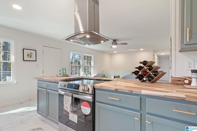 kitchen with island range hood, stainless steel range with electric stovetop, butcher block counters, and ceiling fan