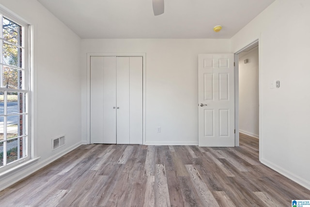 unfurnished bedroom with ceiling fan, a closet, and wood-type flooring