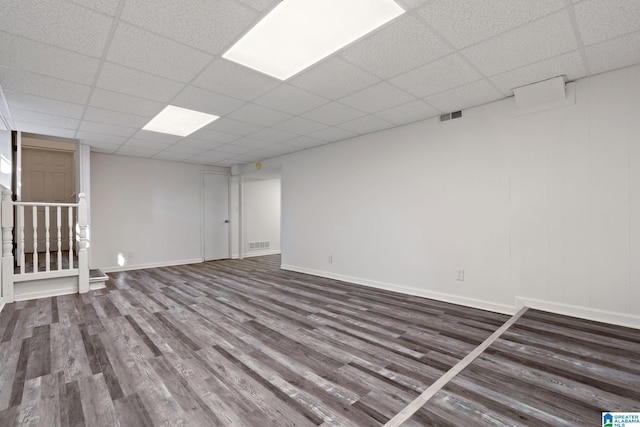 basement with dark hardwood / wood-style flooring and a paneled ceiling