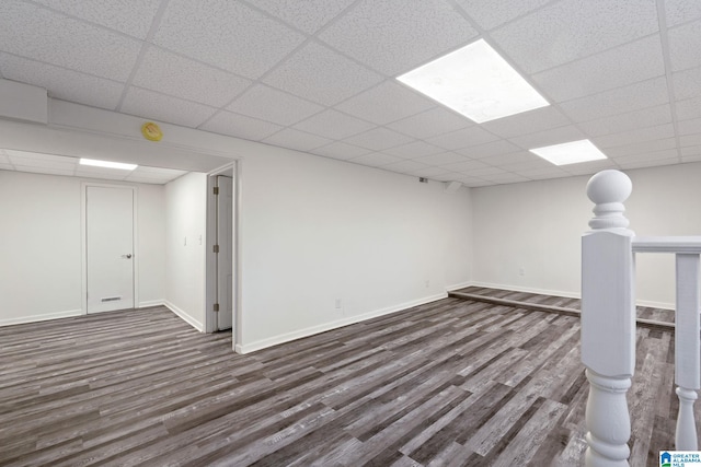 basement featuring a paneled ceiling and dark hardwood / wood-style flooring