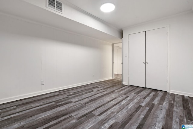 unfurnished bedroom featuring dark hardwood / wood-style flooring, crown molding, and a closet