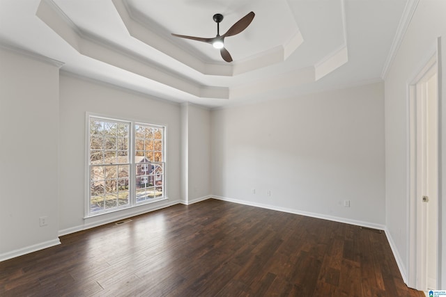 empty room featuring ceiling fan, ornamental molding, dark wood-type flooring, and a tray ceiling